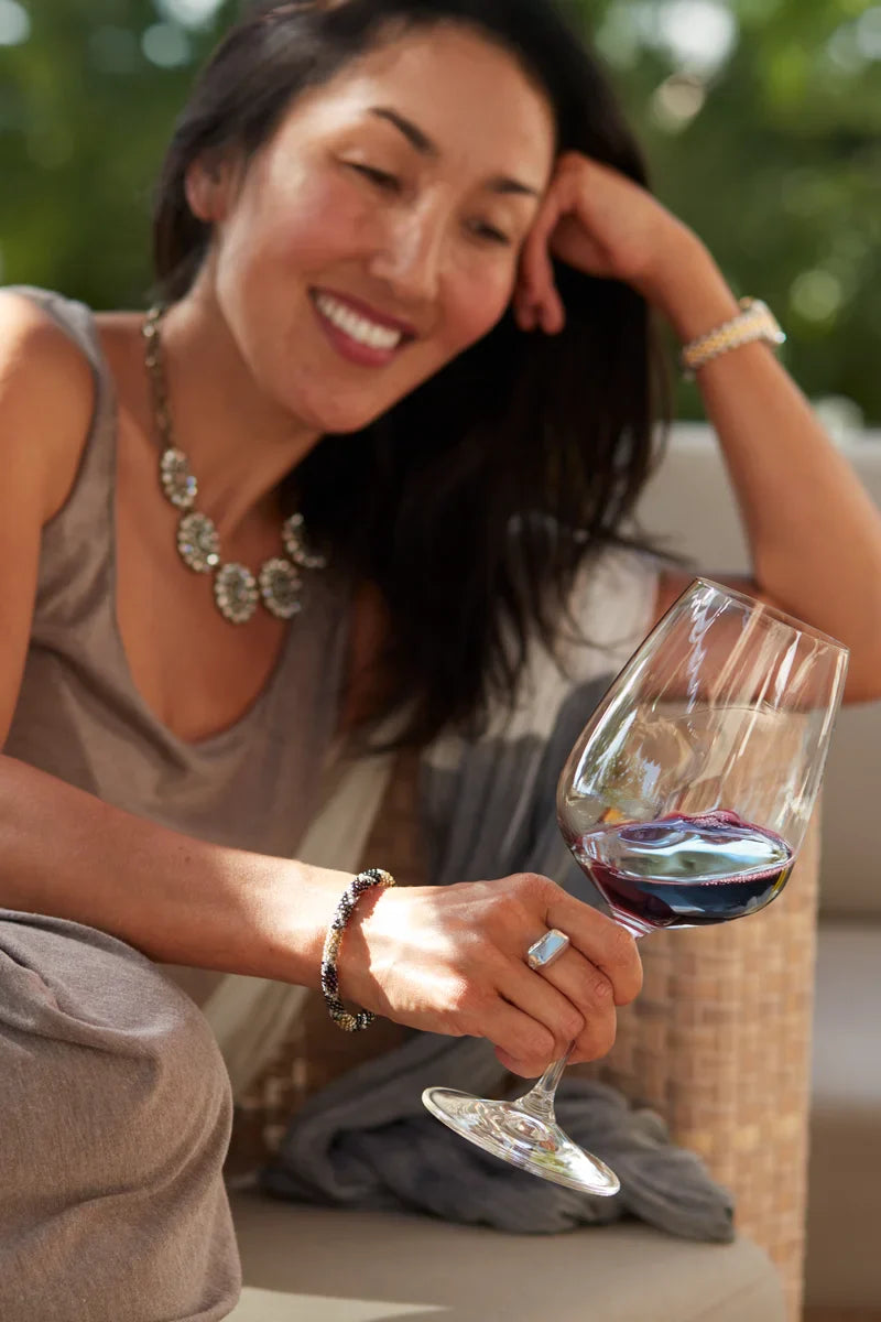 Woman smiling while holding a glass of 2021 HALL Eighteen Seventy-Three Cabernet Sauvignon