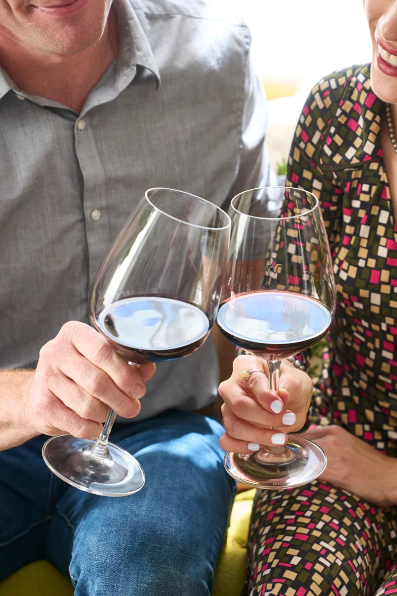 Smiling couple toasting with glasses of 2020 HALL Craig's Cabernet Sauvignon