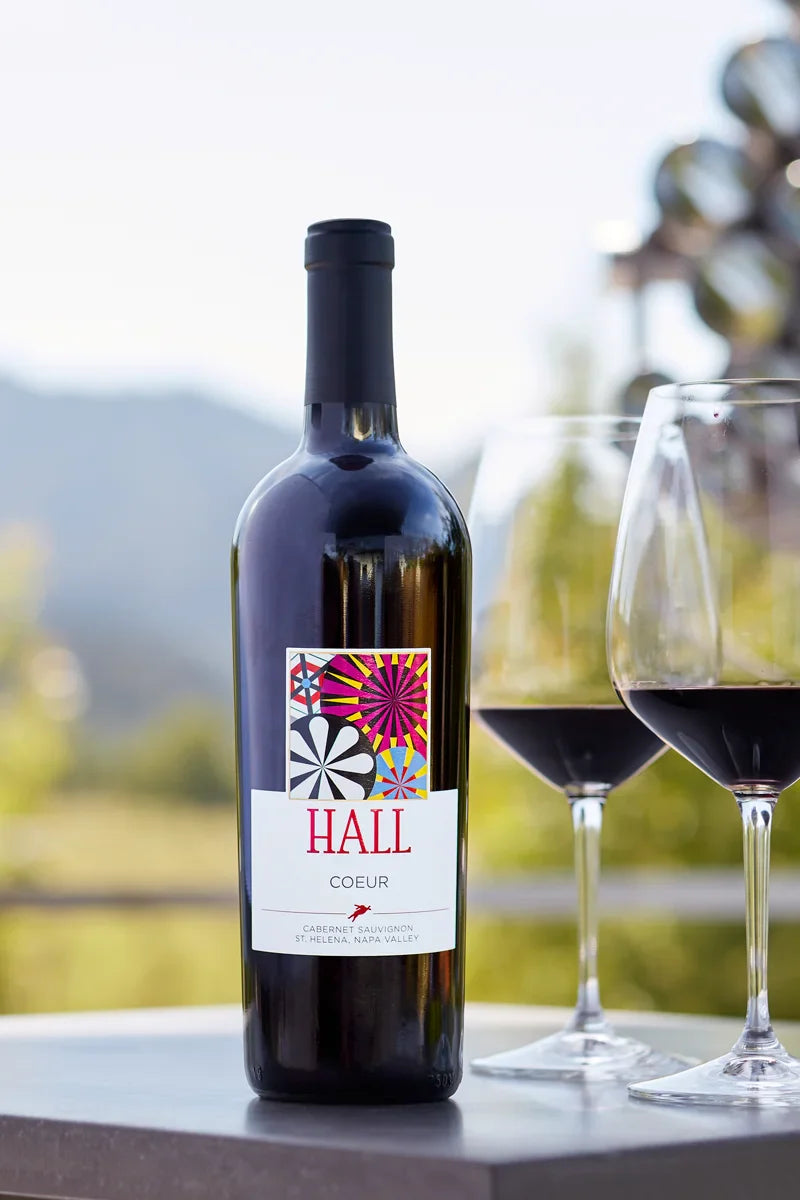 Image of a bottle of 2022 HALL Coeur Cabernet Sauvignon next to two glasses of red wine.