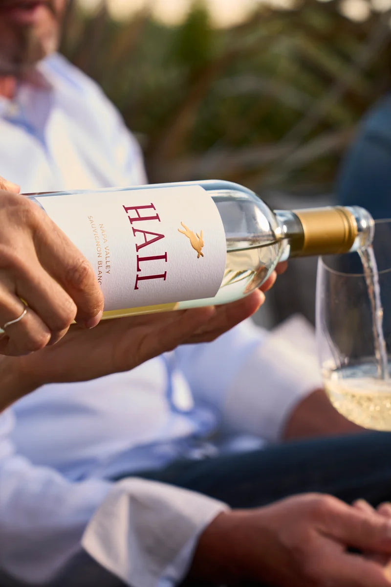 Image of 2024 HALL Napa Valley Sauvignon Blanc being poured into a glass held by a man in the background.